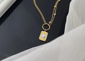 Détail d'une chevillère dorée en acier titane avec un élégant pendentif papillon blanc.