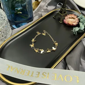 Vue détaillée d'un bracelet de cheville papillon en acier titane doré sur plateau.