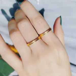Close-up of minimalist gold textured titanium steel rings worn on index and middle fingers