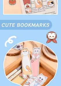 Close-up of cute cartoon cat paper bookmarks displayed on a wooden desk with a notebook