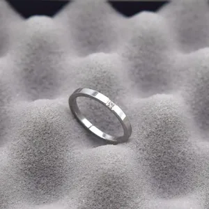 Macro detail of a minimalist silver titanium steel ring placed on a textured grey background