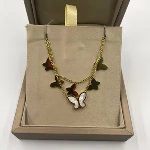 Vue détaillée d'une chaîne de cheville papillon dorée avec breloques en nacre en coffret.