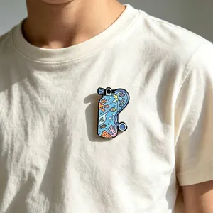 Gedetailleerd beeld van een emaille duikflesspeld met kleurrijk zeeleven op t-shirt