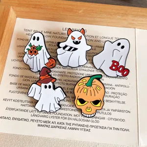 Halloween enamel pins featuring ghosts and pumpkin skull designs on a prop background
