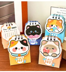Assorted 2027 mini desktop calendars with cute cartoon cat designs for office decor.