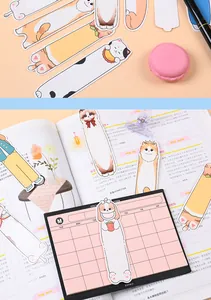 Detailed close-up of cute cartoon cat and dog paper bookmarks used inside a planner book