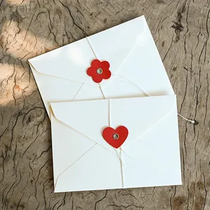 Sobres elegantes en color crema con cierre de cordel y detalles rojos de corazón/flor