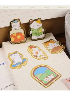 Detailed view of multiple gold-plated cartoon cat bookmarks on a grid notebook page.