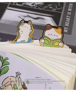 Close-up view of cute cartoon cat metal bookmarks clipped onto white book pages for students