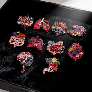 Detailed shot of floral anatomical organ enamel pins set on black velvet display