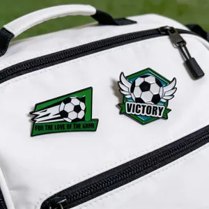 Dettaglio di spillette in smalto a tema calcio con scritta Victory su zaino bianco