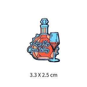 Vue détaillée d'un pin's en émail avec bouteille de vin et verre avec texte Age My Own Way