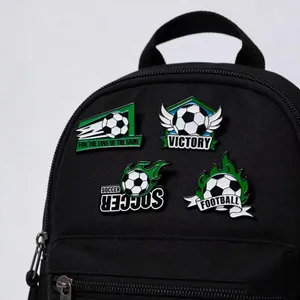 Dettaglio di spille in smalto a tema calcio decorate su uno zaino nero.