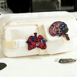 A detailed macro view showing floral anatomical brain and lung enamel pins attached to a bag
