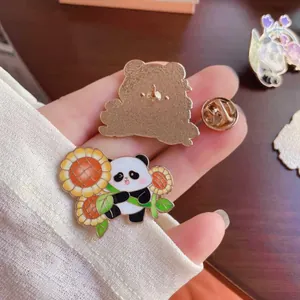Macro detail of a cute panda enamel pin with sunflower design and secure back clasp