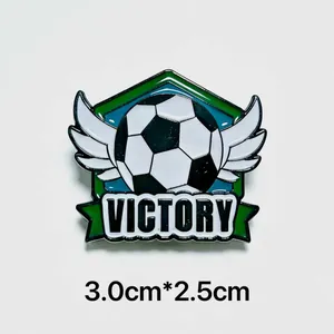 Dettaglio ravvicinato di una spilla da calcio alata con testo victory e misura cm