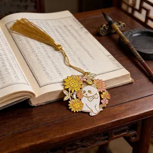 Detailed view of a metal cat bookmark with sunflowers and a golden tassel on a book