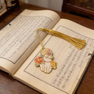 Detailed macro of a metal cat bookmark with golden tassel on an open antique book.