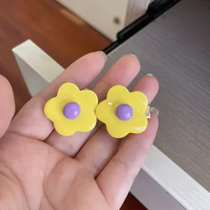 Close-up view of a cute candy-colored flower hair clip held by hand for kids.