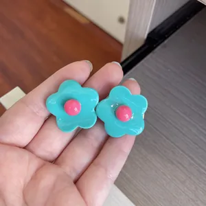Detailed view of cute mint green and pink candy-colored flower hair clips held in hand
