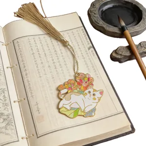 Elegant cat metal bookmark with long golden tassel on a vintage thread-bound book