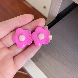 Close-up of cute bright pink flower hair clips held in hand showing resin material details