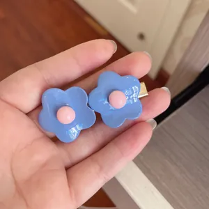 Close-up macro view of cute blue flower hair clips with pink centers held in a hand