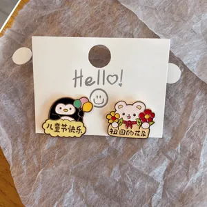 Detailed view of cute cartoon penguin and bear enamel pins on a white display card.