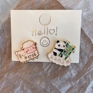 Detailed close-up of cute cartoon sheep and panda enamel pins on a white display card