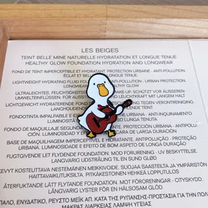 Macro view of a cute cartoon white duck playing a miniature guitar enamel pin