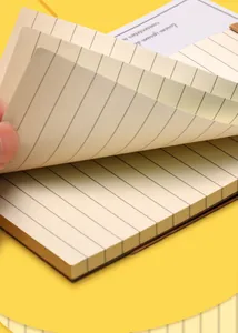Detailansicht eines Taschennotizblocks mit linierten Seiten auf gelbem Hintergrund