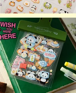 Close-up of cute panda astronaut PET stickers held by a green clip on a green notebook.