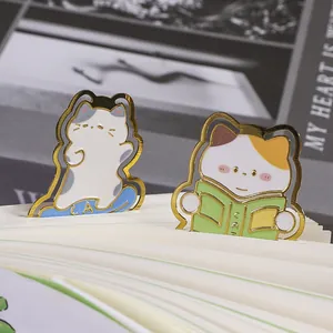 Deze set van schattige metalen kattenwijzers met gouden randen op open boekpagina's