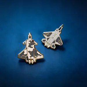Close-up of fighter jet metal lapel pins with camouflage and mechanical details.