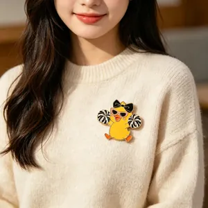 Macro view of a cute yellow cheerleader duck enamel pin styled on a knit sweater.