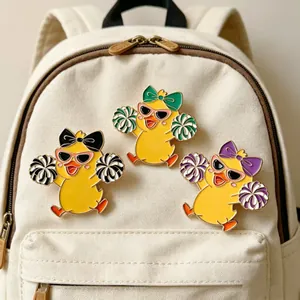 Set of three cute cheerleader duck enamel pins pinned on a white canvas school backpack
