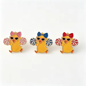 Three cute cartoon cheerleader duck enamel pins in pink, blue, and red colors.
