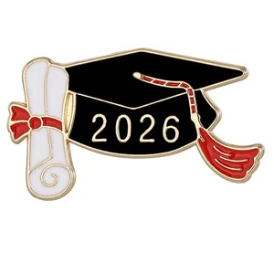 Primer plano detallado del pin de esmalte con birrete y diploma de graduación 2026