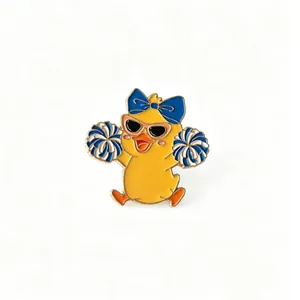 Detailed view of a cute cartoon cheerleader duck enamel pin with blue pom-poms.