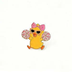Close-up detail of a cute cartoon cheerleading duck enamel pin with pink pom-poms
