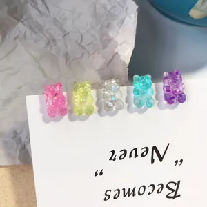 Detalle macro de cinco pendientes de botón con forma de ositos de goma en tarjeta blanca