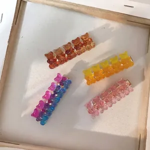 Detailed view of four colorful glittery resin gummy bear hair clips in a wooden frame