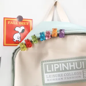 Colorful gummy bear brooches pinned on a light beige and blue backpack detail view