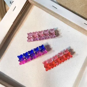 Detailed view of three colorful glittery resin bear hair clips on a white canvas