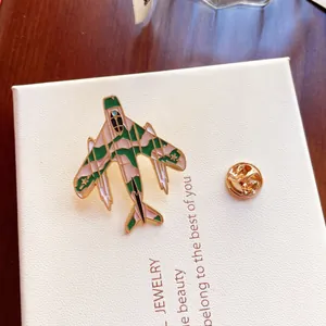 Detailaufnahme einer Emaille-Anstecknadel in Form eines Kampfjets auf einer Geschenkbox