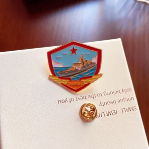 Macro detail of a commemorative metal enamel pin featuring a naval warship and red star.