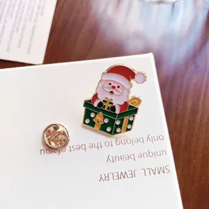 Λεπτομερής προβολή μιας χαριτωμένης καρφίτσας σμάλτου Άγιου Βασίλη σε λευκό κουτί κοσμημάτων
