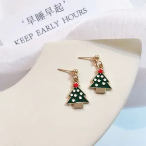 Macro detail of Christmas tree enamel drop earrings with gold trim and white dots