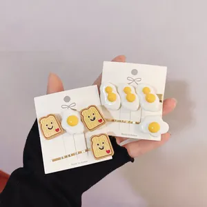 Close-up of cute toast and fried egg hair clips with smiley faces on white cards