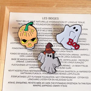 Close-up detail of Halloween enamel pins featuring a pumpkin skull and cute ghosts